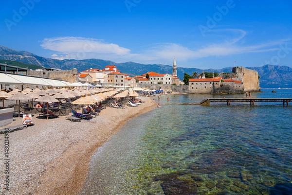 Fototapeta Plaža Ričardova Glava (Richard's Head Beach) against the walls of the Old Town of Budva on the coast of the Adriatic Sea in Montenegro
