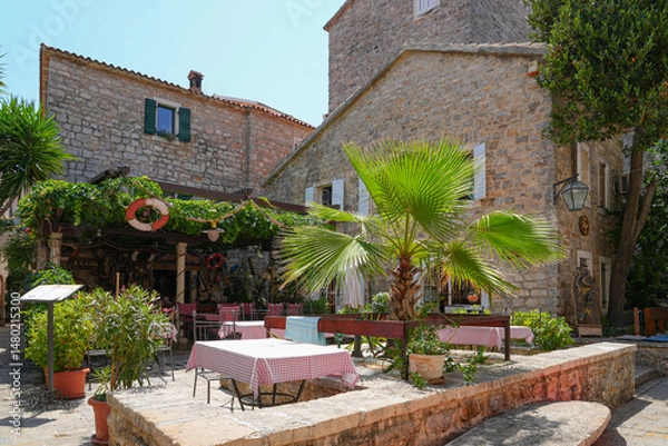 Fototapeta Restaurant terrace in the Old Town of Budva, a walled coastal city built by the Venetian Republic along the coast of the Adriatic Sea in Montenegro