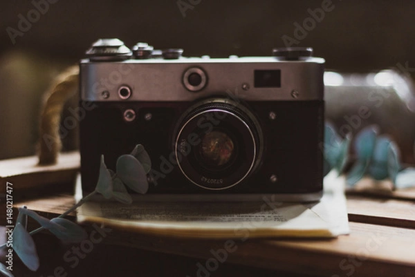 Fototapeta Retro camera on old book and eucalyptus branch on wooden background. Vintage style