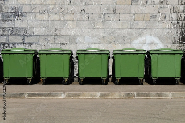 Fototapeta Zielone pojemniki na śmieci stojące w rzędzie na tyłach budynku przemysłowego.
