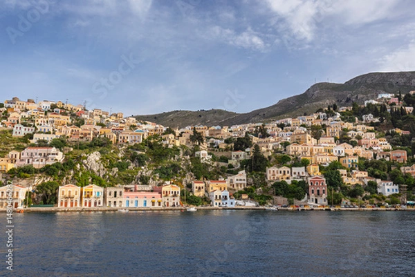 Fototapeta Colorful buildings on a hillside in the idyllic town of Symi by the Aegean Sea on Symi (Simi, Syme) island in Greece on a sunny day.