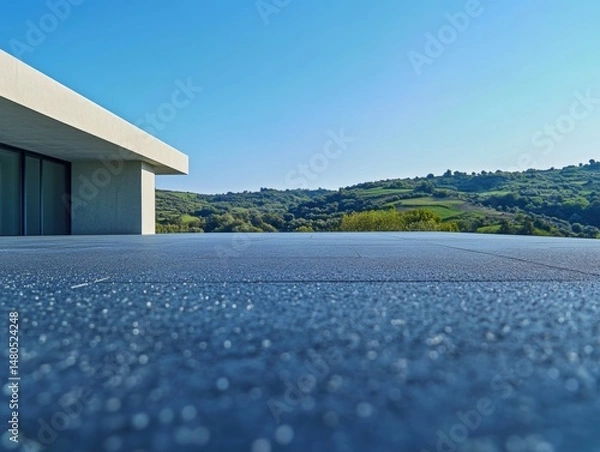 Obraz the roof surface, overlooking green hills and blue sky in the distance. The asphalt is gray with small white particles on it. minimalist architectural building with flat roofs.