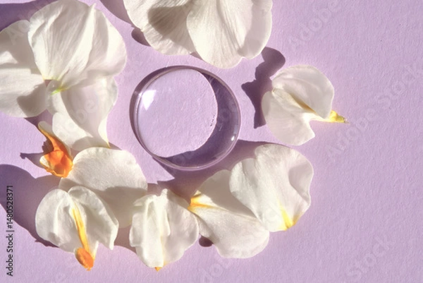 Fototapeta A drop of micellar water on a purple background with flower petals.