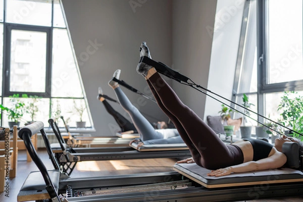 Fototapeta A detailed closeup of a foot work and core exercise on a Balanced Body Reformer machine illuminated by sunlight