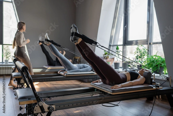 Fototapeta A detailed closeup of a foot work and core exercise on a Balanced Body Reformer machine illuminated by sunlight