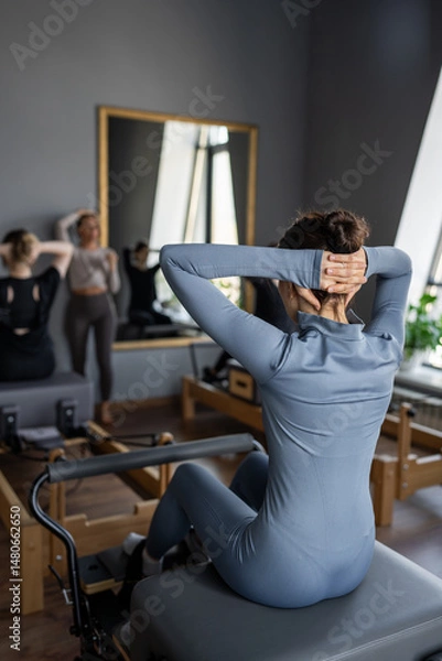 Fototapeta Woman doing rotation exercise on Pilates Reformer for the chest and back muscles, focusing on flexibility, strength, and control with determination