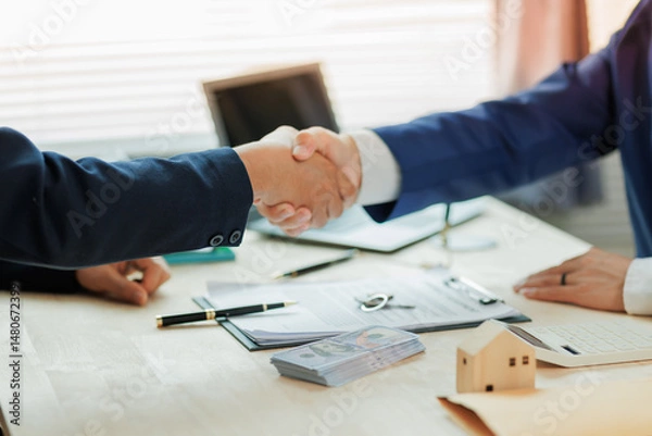 Fototapeta A real estate agent and client shake hands, marking a successful agreement in the home buying process.