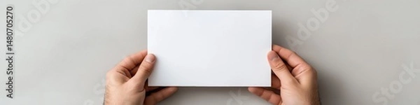 Obraz A person is holding a white card in their hand. The card is blank, and the person is holding it up to show it. Concept of emptiness or potential