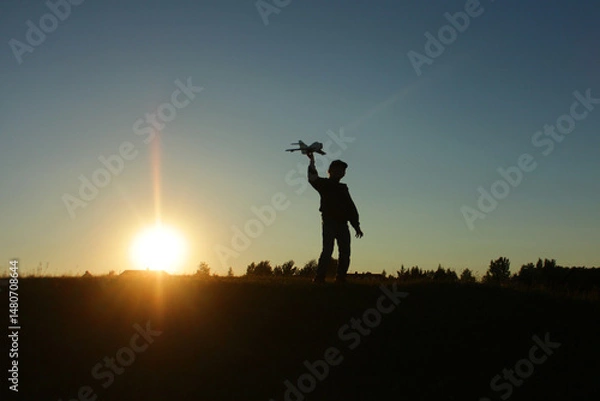 Fototapeta A little boy is playing outside with a toy airplane that he made himself. childhood