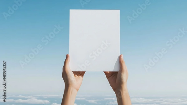 Fototapeta Holding a blank white card against a serene sky backdrop, symbolizing a fresh start, a blank slate, and endless possibilities for new ideas.