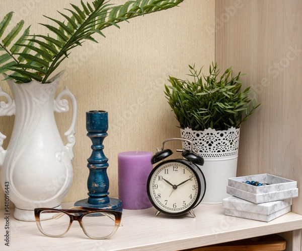 Obraz A white vase with a blue candle and a clock on a shelf
