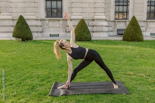 Obraz A midage woman, embodying strength and balance, practices yoga outdoors in a beautifully serene setting, fully showcasing her dedication to health and wellness among the picturesque surroundings