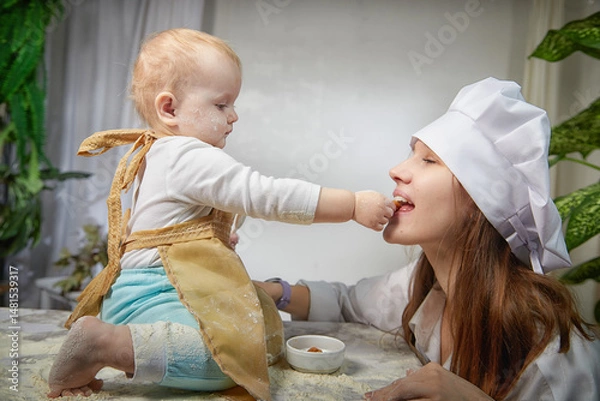Fototapeta Mother and daughter in aprons joyfully playing with flour during a fun kitchen-themed photo shoot at home