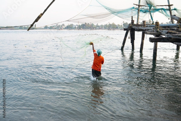 Obraz Fisherman throwing traditional fishing net into the ocean, Kochi in India, industry at arabian sea coast, chinese Cheena vala or tangkul