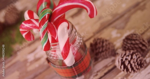 Obraz Showcasing glass jar with plaid ribbon holding candy canes on rustic tabletop with pinecones
