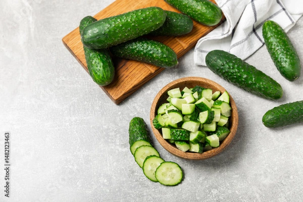 Fototapeta Cucumber on wooden background. Slice of cucumber on background. Fresh organic green cucumbers gherkin. Vegan. Salad ingredient. Farm vegetables. Cut vegetables with knife. Space for text. Copy space