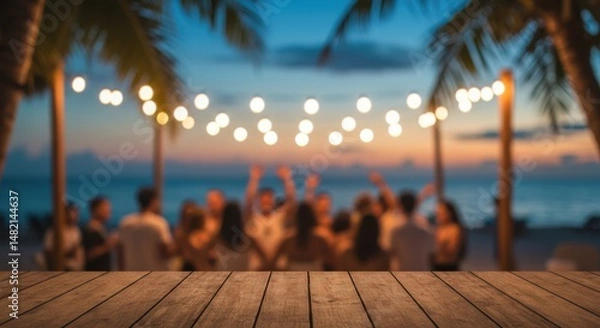 Fototapeta Blurred Beach Party at Sunset with Wooden Table in Foreground