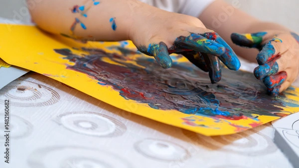 Fototapeta Joyful little girl engaging in fun educational finger painting activity, exploring creativity with vibrant colorful paints and learning through playful art exploration