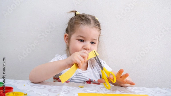 Fototapeta Joyful toddler girl enjoying creative art activity with colorful finger painting and cutting paper, developing fine motor skills and artistic imagination at home