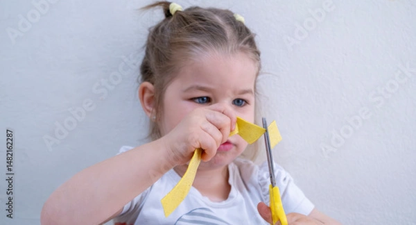 Fototapeta Joyful toddler girl enjoying creative art activity with colorful finger painting and cutting paper, developing fine motor skills and artistic imagination at home