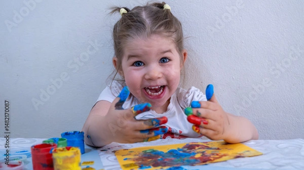 Fototapeta Happy Little Girl with Colorful Painted Hands, Joyfully Playing with Finger Paints on Bright Paper, Expressing Creativity and Fun During Early Childhood Art Activity
