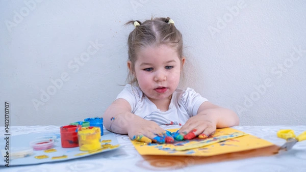 Fototapeta Adorable Little Girl Joyfully Exploring Finger Painting with Bright Acrylic Colors, Showing Painted Hands and Creative Artworks, Fun Early Childhood Education Activity