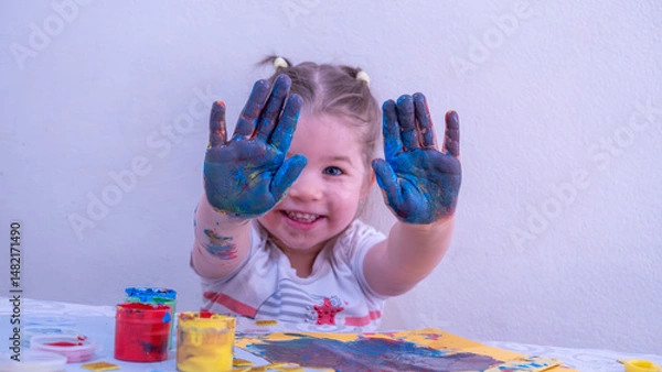 Fototapeta Smiling Little Girl Showing Hands Covered in Bright Acrylic Paint, Joyfully Participating in Creative Finger Painting Activity, Fun Early Childhood Art and Learning Concept
