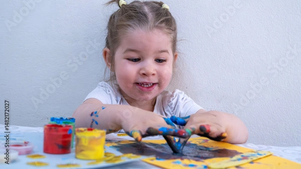 Fototapeta Cheerful Little Girl Enjoying Fun Finger Painting Activity, Exploring Creativity with Bright Acrylic Colors, Early Childhood Education and Fine Motor Skill Development