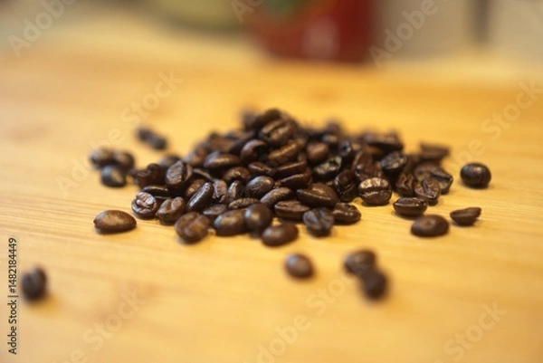 Obraz Roasted coffee beans on a wooden surface. long_title:A close-up view of freshly roasted coffee beans scattered across a warm, wooden table, showcasing