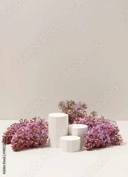 Obraz Beauty cosmetics product presentation scene made with white miniature columns surrounded by fresh lilac flowers on soft neutral background. Vertical photography.