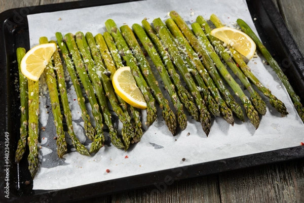 Fototapeta Grilled asparagus with lemon on baking tray