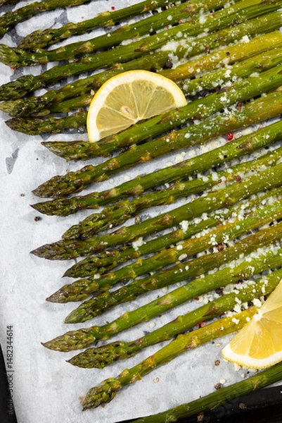 Fototapeta Grilled asparagus with lemon on baking tray and hard cheese