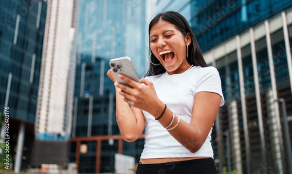 Obraz A Young Woman Engaged with Her Smartphone While Surrounded by a Vibrant, Energetic Urban Setting