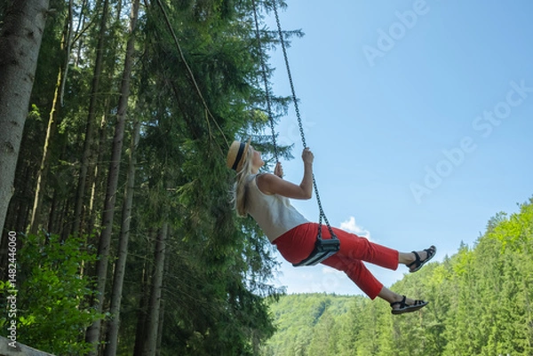 Obraz Woman Enjoying Nature on a Swing. Embraces lightness and freedom, surrounded by fresh air and greenery. Relaxation, happiness, connection to nature	