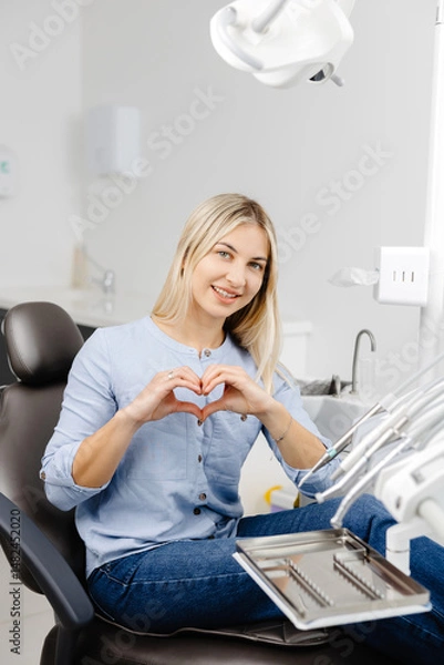 Fototapeta Patient showing heart shape with hands sitting in dentist chair
