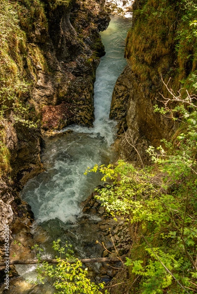Fototapeta Dramatic Narrow Canyon In Leutaschklamm Gorge: Crystal-Clear Turquoise Mountain Stream Winding Through Steep Rocky Cliffs Surrounded By Moss-Covered Walls And Lush Greenery In Tyrol, Austria