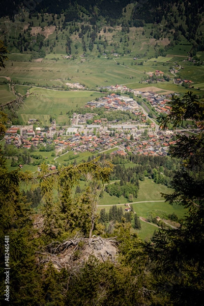 Fototapeta Stunning Aerial View Of Oberammergau Town: Picturesque Bavarian Village Nestled Between Lush Green Meadows, Dense Forests, And Majestic Rocky Peaks In The Scenic Ammergau Alps Region