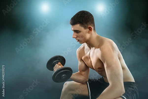 Obraz Young Man Working Out in the Gym with Weights. Focused and determined, he lifts during an intense strength training session. Fitness, motivation, and healthy lifestyle