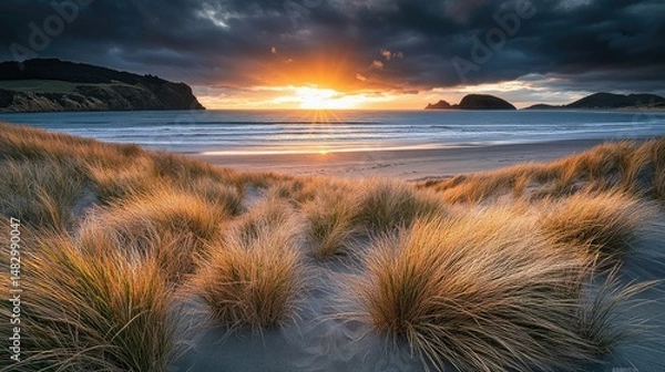Fototapeta A serene beach scene at sunset, featuring gentle waves lapping against the shore.