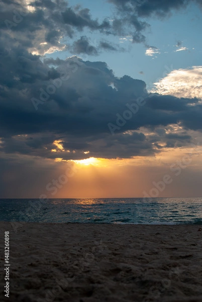 Obraz Soft golden light illuminates an empty sandy beach and the calm Black Sea in Odesa Ukraine after a storm has passed, with lingering dark clouds creating a serene and hopeful dawn scene.