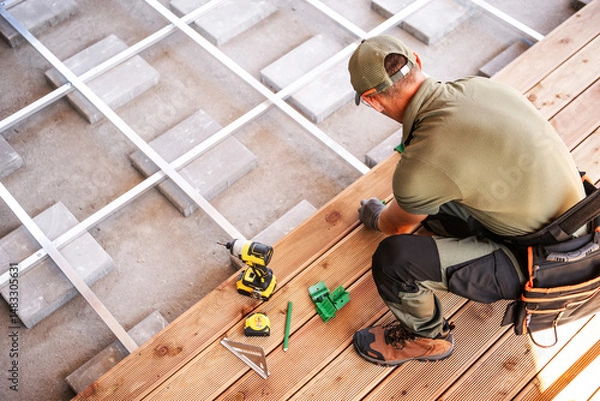Fototapeta Construction Worker Installing Wooden Flooring in a Residential Space During Daylight Hours With Tools Nearby