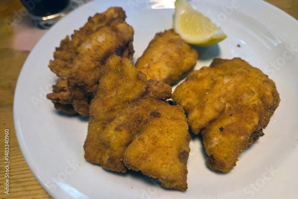 Fototapeta Crispy Fried Chicken Pieces with Lemon Garnish on White Plate