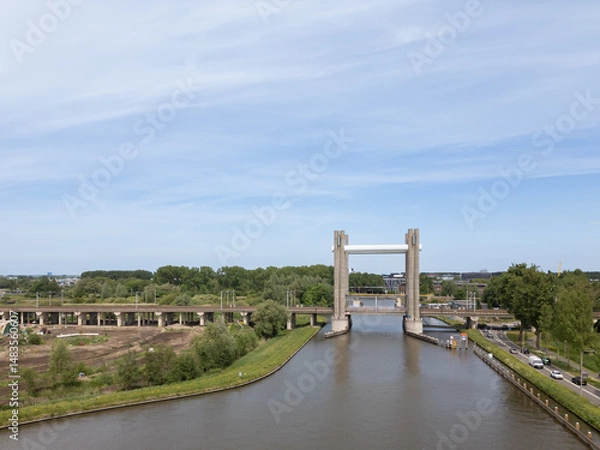 Fototapeta Netherlands civil engineering railway bridge in Dutch city Gouda, Hoge Gouwespoorbrug over Gouwe Canal train link transportation infrastructure connection on sunny day with cars 