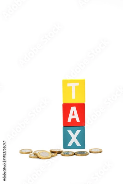 Fototapeta British one pound coins in front of coloured wooden blocks spelling the word Tax isolated against a plain white background
