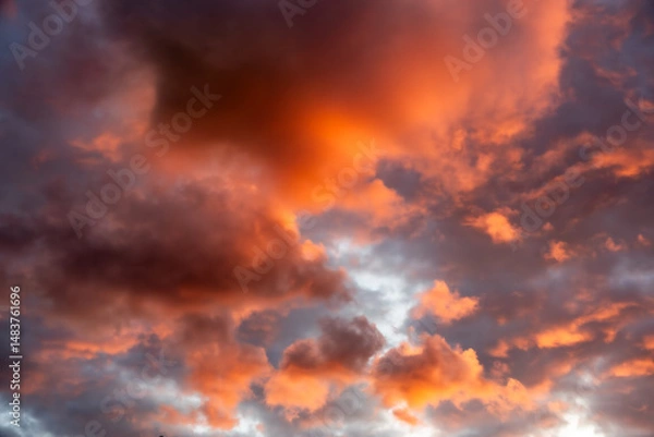 Obraz Evening sky full of clouds, illuminated by the setting sun, shining in strong orange tones