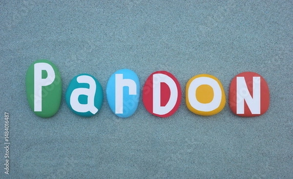 Fototapeta Pardon, the action of forgiving or being forgiven for an error or offence, creative word composed with multi colored hand painted stone letters over green sand