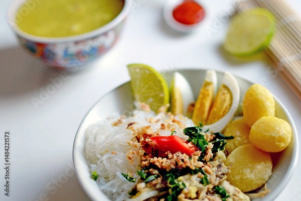 Fototapeta A steaming bowl of soto daging ayam, a traditional Indonesian culinary chicken soup stew with glazed noodles 