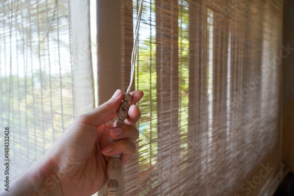 Obraz wooden horizontal blind,close,men hand on the window in the morning