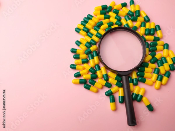 Fototapeta Medicine pill and magnifying glass on a pink background with copy and text space