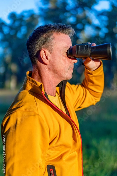 Fototapeta Man using binoculars in nature